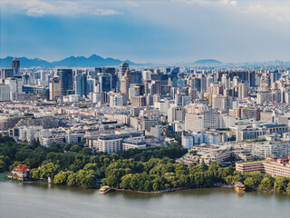 Fototapeta premium Aerial shot of Hangzhou city, West Lake and surrounding mountains framed under white clouds
