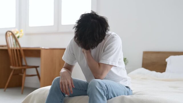 肩を押さえてつらそうに座る30代の日本人男性