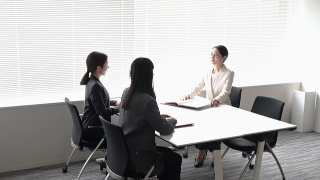 会議室で歩きながら打ち合わせを行う20代から40代の日本人ビジネスパーソン3人
