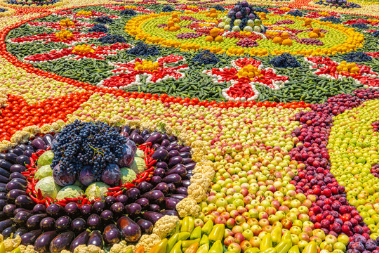 Colorful decorative mosaic pattern made of fresh fruits and vegetables arranged in spiral at Tajik harvest festival