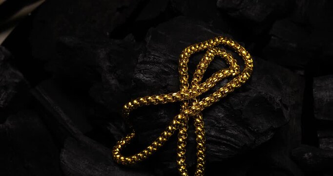 Closeup shot of gold necklaces on charcoal with rotating
