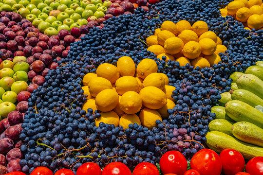 Colorful fruit and vegetable mosaic display with grapes, peaches, zucchini and tomatoes at Tajik harvest festival bazaar