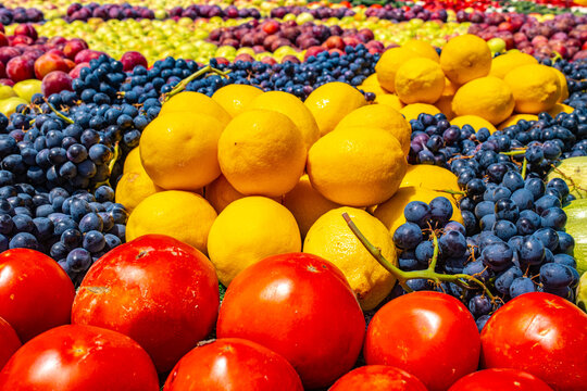 Colorful arrangement of grapes, lemons, tomatoes at Tajik harvest festival market display