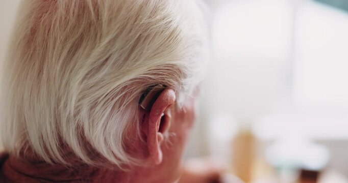 Elderly, woman and ear with hearing aid for audio, sound or awareness for balance in house. Senior, female person or retirement with medical senses for speech, noise or treatment in nursing home