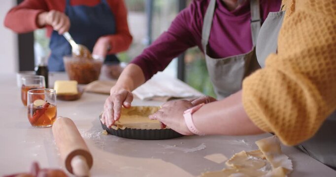 Diverse female friends baking pressing pastry into fluted tart pan at counter with bowl, copy space