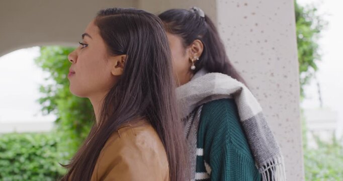 Two women arriving at front porch, visiting friend, brown jacket pressing doorbell, friend smiling