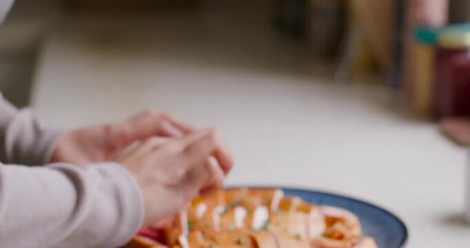 African American woman seeing almonds topping beans on plate on counter finishing plating in apron