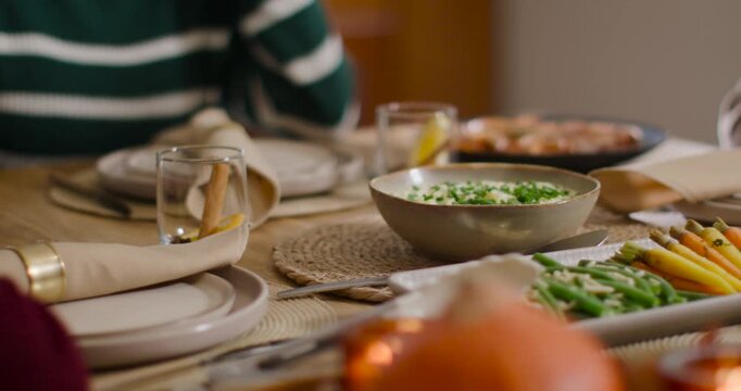 Indian woman in green knit laughing touching necklace while friend talking at table, copy space