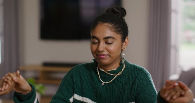 Hands releasing Indian woman in green sweater opening hands, clapping folding at table before meal
