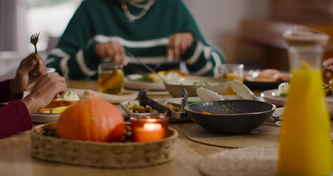 Diverse women sharing meal at home, Indian woman in green sweater cutting food near pumpkin tray