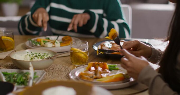 Diverse female friends cutting food and sharing mashed potatoes at home while camera pulling back