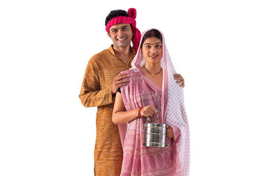 Portrait of happy couple standing with lunch box against white background