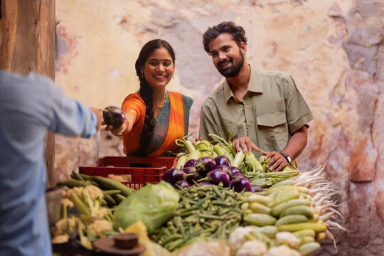Young couple buying vegetable from street market