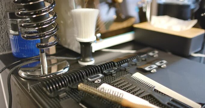 Camera is sliding forward and racking focus, revealing barber tools on black mat for styling