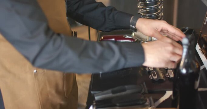 African American male barber wearing brown apron arranging clippers and guards at salon for haircut