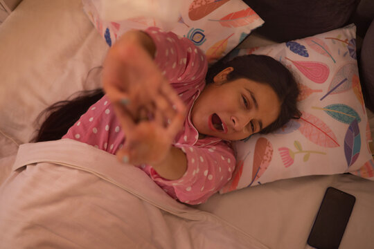 Portrait of teenage girl yawning on bed 