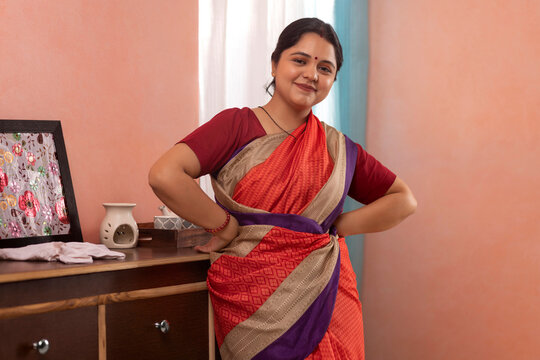 Portrait of a young woman looking at camera with hands on waist during dusting