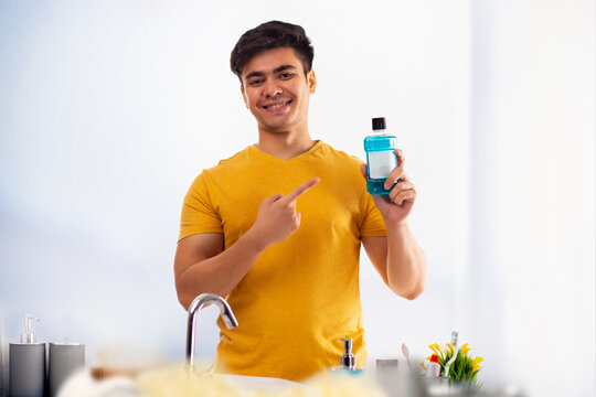 Smiling man pointing at hand wash holding in his hand