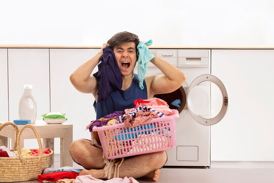 Portrait of frustrated young man screaming while doing laundry