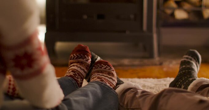 African-American couple left in red jumper leaning nudging wool socks at home by stove warming feet