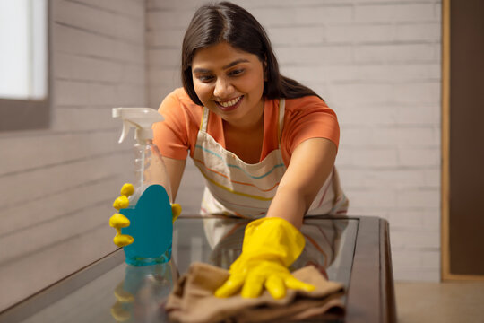 Woman cleaning the surface of table at home