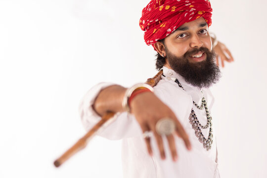 Portrait of Rajasthani man with stick on shoulder standing against white background