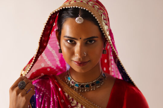 Close-up portrait of a cheerful Rajasthani young woman against white background