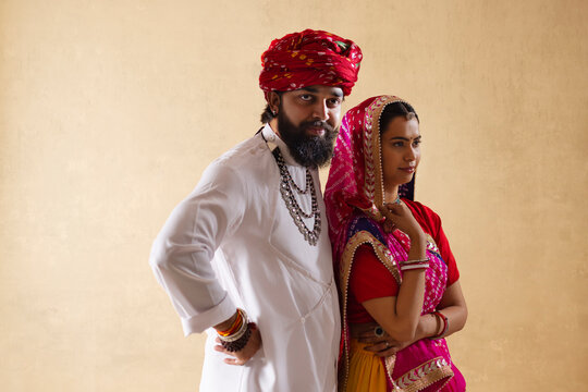 Portrait of Rajasthani couple standing against plain background
