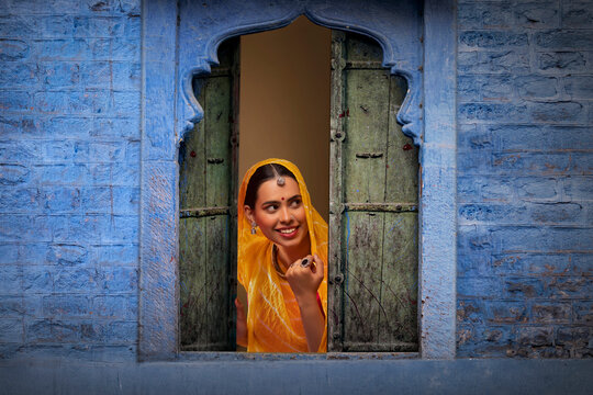 Rajasthani young woman peeking out through window