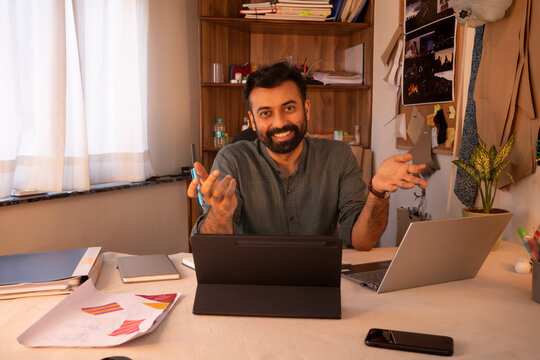 A male fashion designer using laptop and tablet in his studio
