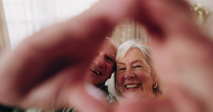 Elderly, face or happy couple with heart hands for love, commitment or relationship together in home. Portrait, senior man and woman with smile, like emoji or shape for romantic gesture in house