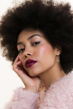 Close-up portrait of a woman with afro hairstyle. Beautiful young lady with warm brown skin and makeup. Fashion model with curly hair.