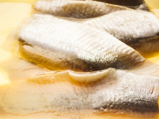 Freshly packed herring fillets in yellow brine. Clear plastic container. Fish scales visible. Food for ready to eat meals. Ready for cooking or eating. Popular tasty sea product. © mark_gusev