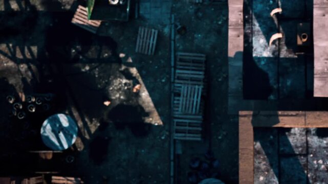 A view of a construction site with various materials scattered on the ground. Old pipes, wood, and debris lay around the area. The image shows part of the construction structure from above.