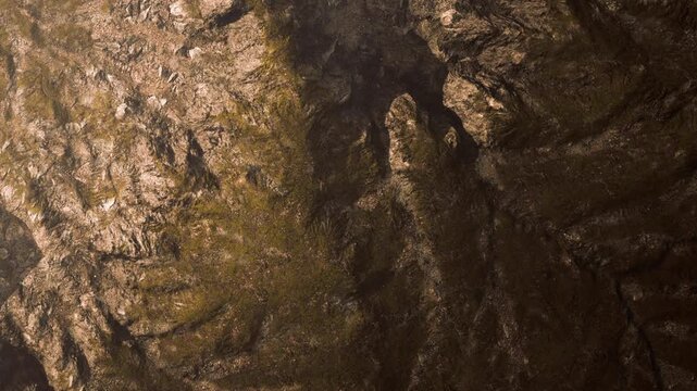 A close view of a rocky surface in sunlight. Different textures can be seen on the rocks. The colors and shapes suggest natural patterns from a rocky landscape.