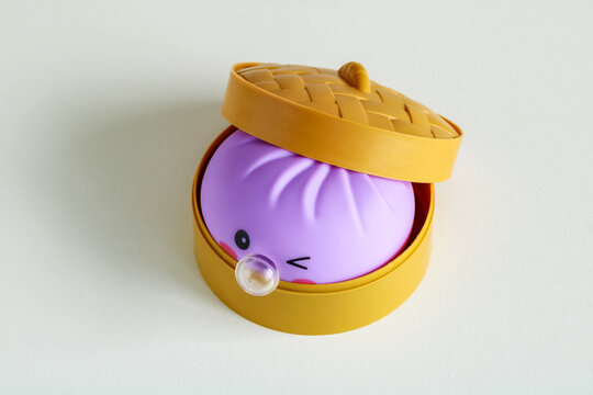 Moscow, Russia - July 09, 2026: Purple squishy dumpling fidget toy with bubble and bamboo steamer container isolated on a white background.