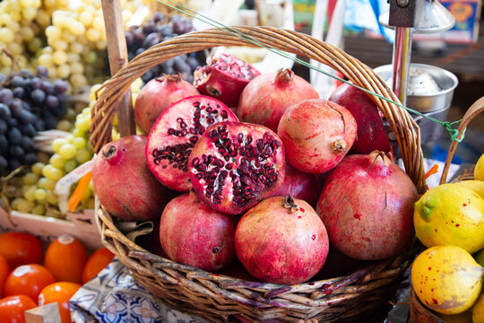 Fresh pomegranates piled high in a woven basket at the Ballaro market in Palermo, Sicily, Italia.