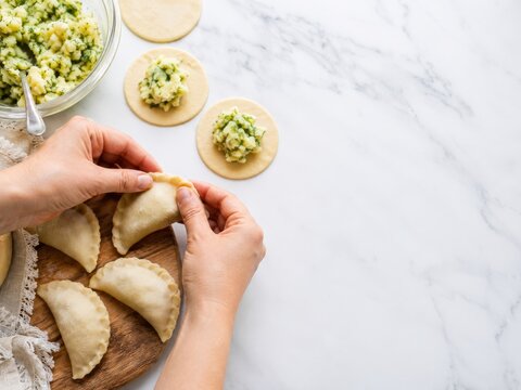 Preparar empanadas con masa y relleno de papa en una mesa de cocina