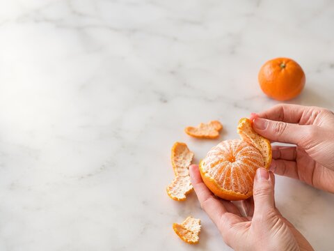Pelar una mandarina en una mesa de m&aacute;rmol en una cocina
