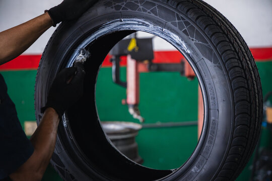 Mechanic hands using a brush to apply mounting paste on a car tire bead. Professional tire replacement and preparation service in an auto repair garage