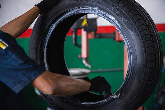 Mechanic hands using a brush to apply mounting paste on a car tire bead. Professional tire replacement and preparation service in an auto repair garage
