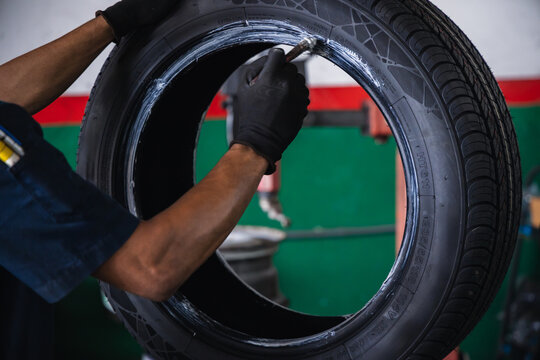 Mechanic hands using a brush to apply mounting paste on a car tire bead. Professional tire replacement and preparation service in an auto repair garage