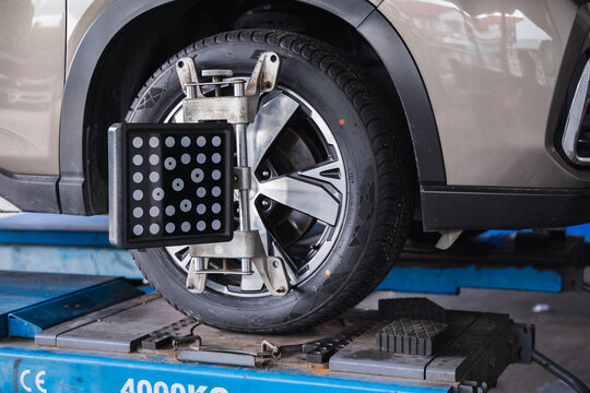 Wheel alignment sensor target attached to a car tire. Professional auto repair garage service for vehicle steering calibration and safety maintenance