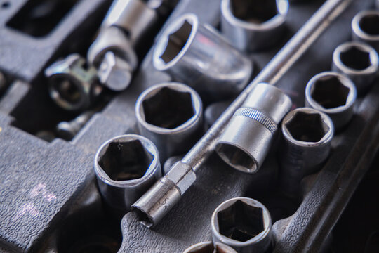 Metallic socket wrench set inside a mechanic toolbox. Assorted professional auto repair tools, garage equipment, and hardware instruments for vehicle maintenance and mechanical fixing