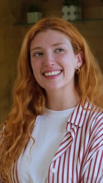 A close-up shot of a happy young woman with beautiful long red hair, smiling and looking joyfully around, conveying feelings of happiness, positivity, and natural beauty.