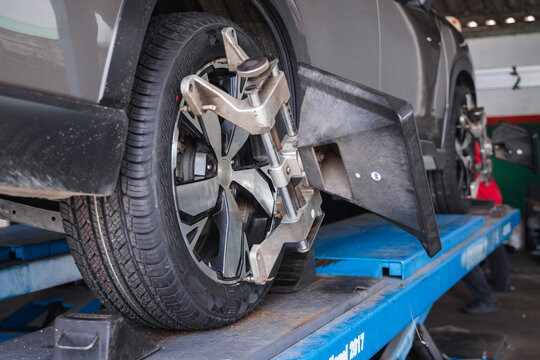 Wheel alignment sensor target attached to a car tire on a scissor lift. Professional auto repair garage service for precise vehicle steering calibration and diagnostics