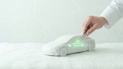 Fototapeta premium Hand of engineer installing glowing green chip into white electric car model with tweezers. Future eco EV technology commercial banner copy space.