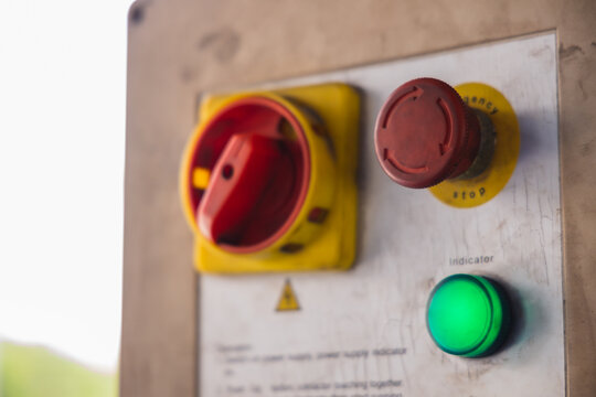 Red emergency stop button and main power switch on an industrial machine control panel. Essential safety equipment for factory or auto repair workshop operations