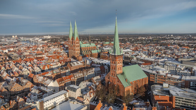 Aerial view of L&uuml;beck old town in winter with snow-covered roofs and historic churches Germany. Aerial view of brick gothic architecture of St. Mary's Church and the distant L&uuml;beck Cathedral in winter