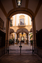 Obraz premium Palermo, Italy; 1st January 2026: Palazzo Comitini courtyard with arches and antique carriages in Palermo.